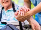 carer holding the hand of a patient