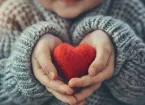 Person holding a red love heart made of wool 