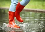 person walking in a puddle wearing wellington boots 