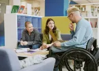 Wheelchair user in a library chatting to friends 
