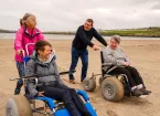 People on a beach, people using beach wheelchairs 