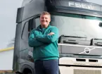 A man leaning against an electric truck with his arms crossed 
