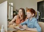 photo of Woman and Boy Smiling While Watching Through Imac