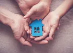 Adult and child hands holding paper house