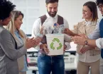 A group of employees in a pleasant atmosphere in the office ,collecting plastic bottles in the recycling bin. 
