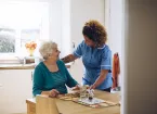 Care worker giving an old lady her dinner in her home.