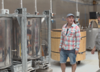 2 men inside a brewery next to tanks