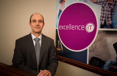Man next to Excellence IT logo