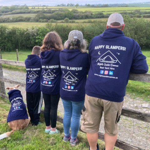 Stephen and family leaning on a fence with their back to the camera wearing branded business hoodies