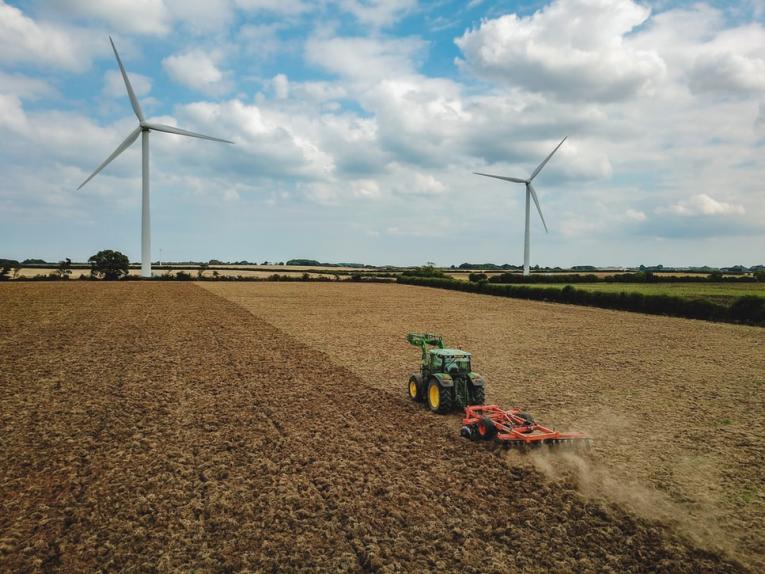 Tractor in field with wind turbines in background
