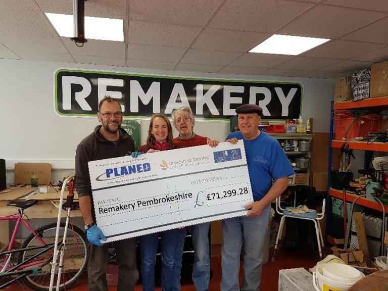 image of beneficiaries at the remakery holding a large cheque for the funding