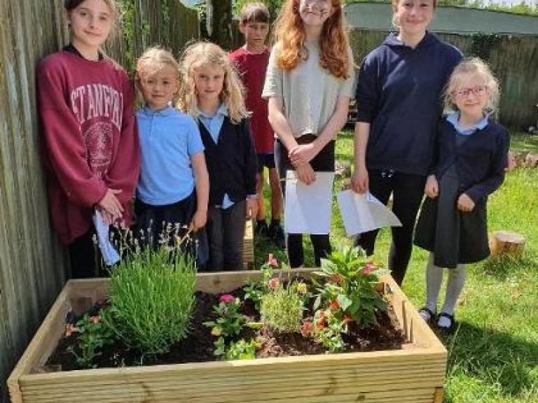 image of children with a raised grow bed with young plants