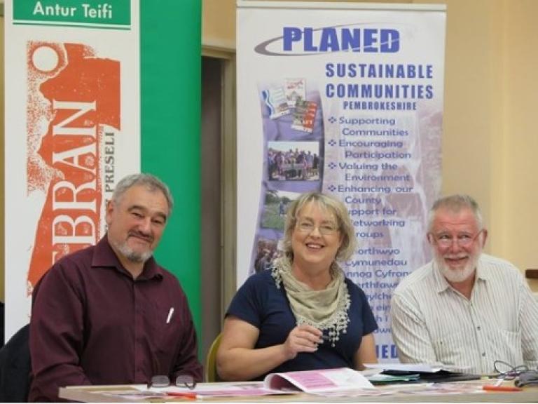 image of three people from Pembrokeshire shares at a desk with planed and antur teifi banners behind